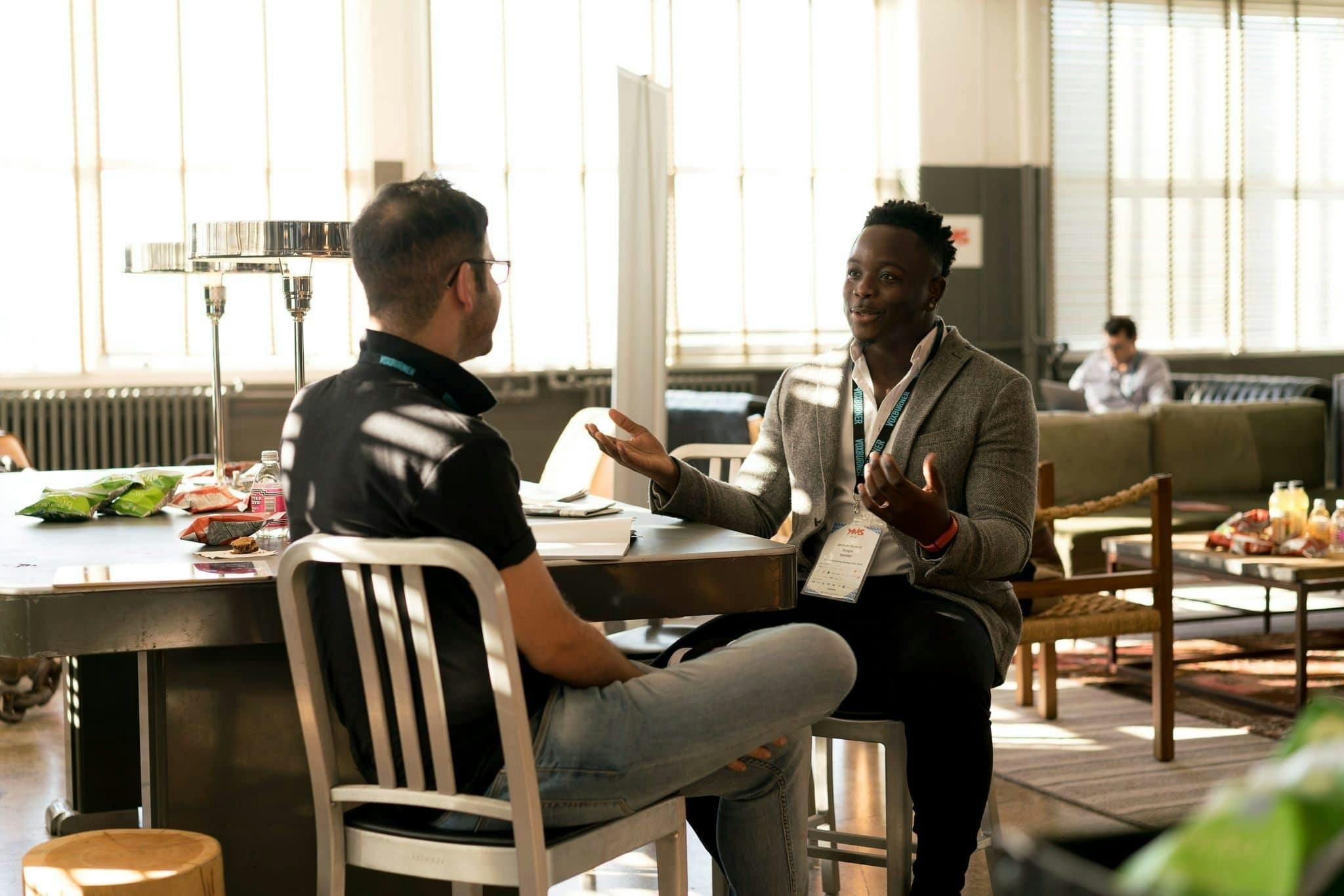 homem conversando com outro homem de forma expressiva em um looby, fazendo networking