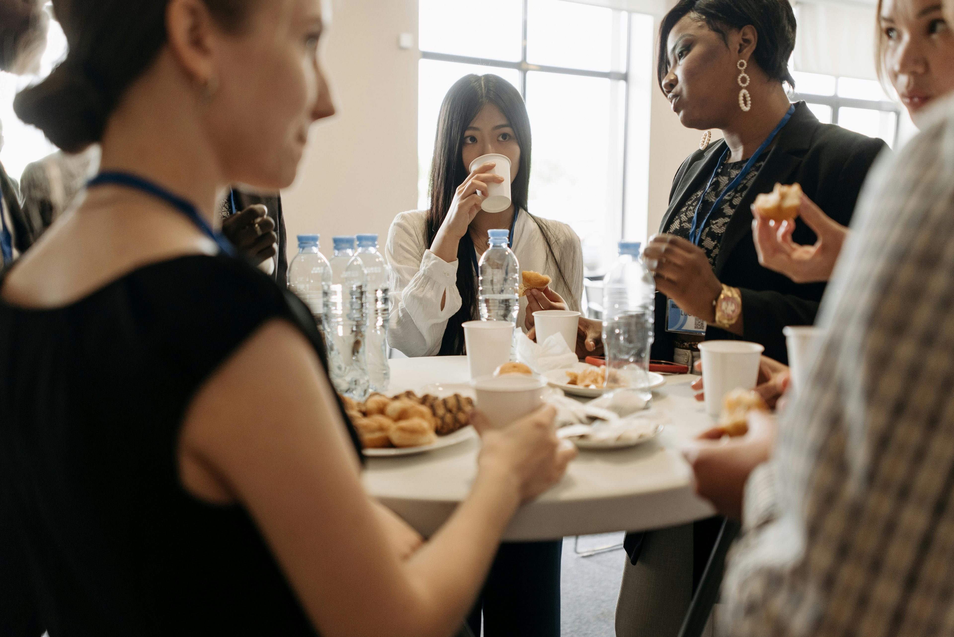 coffee break em evento de networking corporativo, mulheres ao redor da mesa conversando e comendo