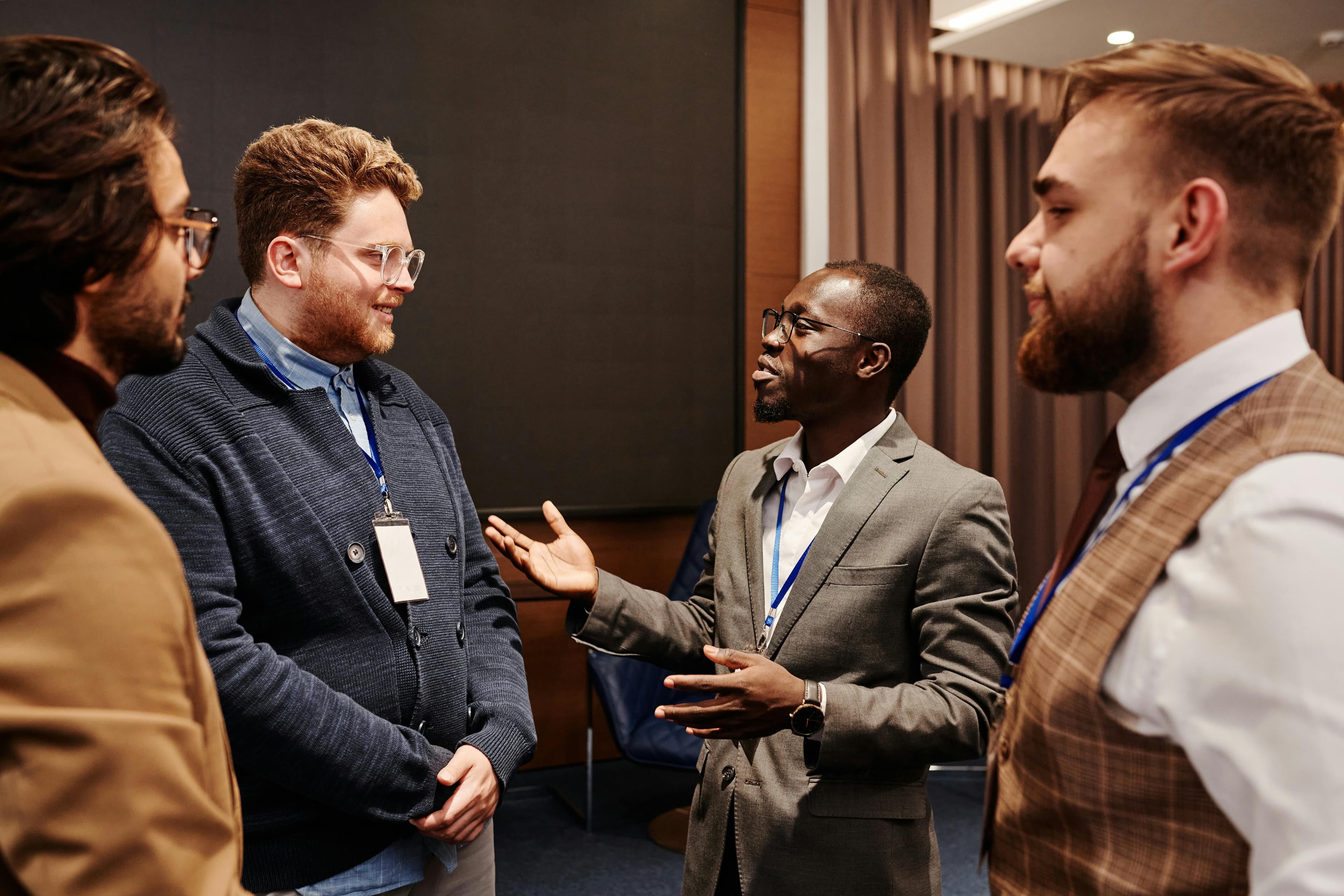 hombres conversando en evento de networking, hombre sonríe mientras el otro dice algo
